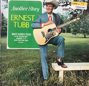 Ernest Tubb 戴著牛仔帽，身穿藍色西裝，在草地長椅上手持結他，旁邊有專輯封面。