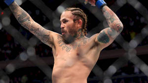 紋身MMA拳手在八角籠內高舉雙臂慶祝勝利。 — 冠軍 壁紙