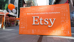 城市廣場上帶有白色圖標的大型橙色Etsy標誌，伴有氣球。
