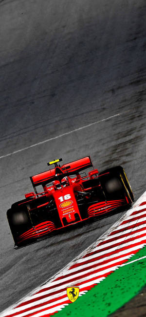紅色法拉利F1賽車在紅白綠路肩的賽道上奔馳。 — iPhone 18 壁紙