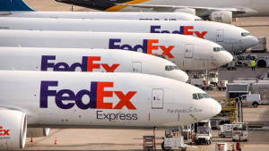 FedEx貨機停泊在機場停機坪，有地勤人員和車輛。