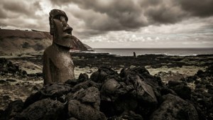 暴風雨天空下火山岩海灘上的古代摩艾石像