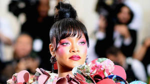 Rihanna 喺時尚活動中身穿花卉長裙，搭配粉紅妝容。