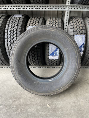 在輪胎倉庫中展示的 Firestone TransForce HT 輪胎，旁邊貨架上有其他輪胎。