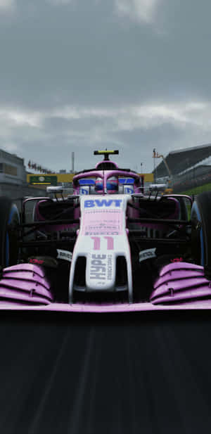粉紅色和白色的 Formula 1 賽車在陰天下的賽道上比賽。