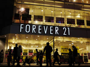 夜晚場景，人們行過一間有日本減價標誌嘅 Forever 21 舖頭。 — 4:3 壁紙