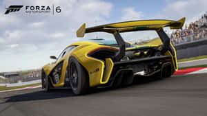 黃色McLaren賽車在賽道上，夕陽下人群圍觀。 — 麥拿侖 GIF 壁紙