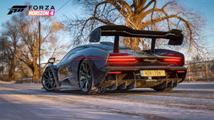 黑色McLaren跑車停泊在雪路上，周圍是光禿禿的樹木，夕陽西下。
