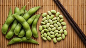 新鮮嘅毛豆莢同剝殼豆喺竹蓆上配筷子。