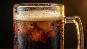 冰凍啤酒杯，帶有冷凝和泡沫，在溫暖燈光下