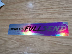 鐳射貼紙，上面寫著「LIVIN LIFE FULL SEND」，放在木頭上。