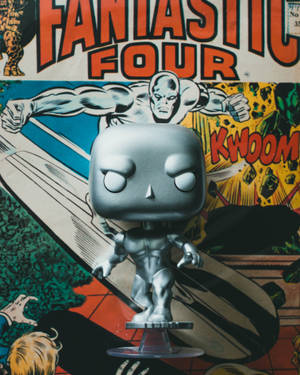 銀色滑翔者Funko Pop！人偶放在透明支架上，背景是神奇四俠漫畫封面。