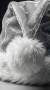 深色背景上的白色天鵝絨聖誕老人帽和 fluffy 絨球