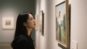 身穿黑色西裝外套的女性在美術館觀看裱框畫作