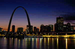 暮色中的 Gateway Arch 與城市天際線，河面倒影