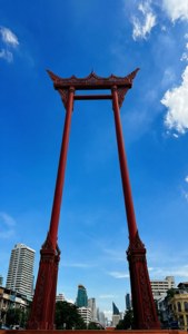 紅色泰式拱門襯著藍天和後面的城市建築