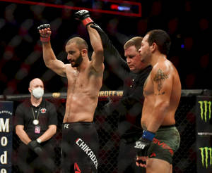 MMA 拳手在八角籠內慶祝勝利，裁判舉起他的手。 — 運動 壁紙