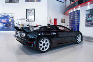 現代汽車博物館中的亮黑色Bugatti EB110跑車及賽車海報。 — 3:2 壁紙