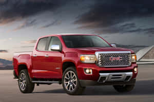 紅色 GMC Canyon 皮卡車在黃昏時停車，背景有山。 — 暮光 壁紙