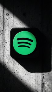 在混凝土牆上發光的Spotify標誌，帶有強烈陰影。