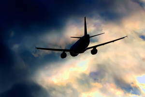 飛機在日落時分穿過色彩繽紛的雲層飛行。 — 飛機 壁紙