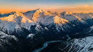 夕陽下的雪山山脈，山谷中有蜿蜒的河流