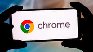 手部拿著顯示 Chrome 瀏覽器標誌的電話。
