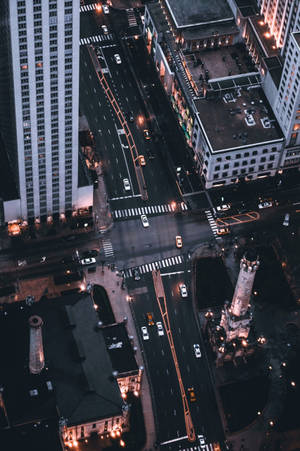 夜晚繁忙城市街道交叉口的鳥瞰圖，有汽車和燈火通明的建築物。