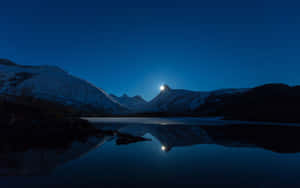 白雪覆蓋的山峰在星光下閃耀，倒映在夜晚平靜的湖面上。