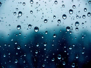 玻璃上的雨滴，背景模糊藍灰色