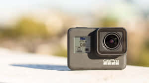 GoPro 相機在陽光明媚的戶外表面上，背景模糊。 — Studio Display 壁紙