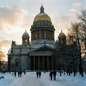 人們在日落時分沿著雪徑走向一座金色圓頂的宏偉大教堂。