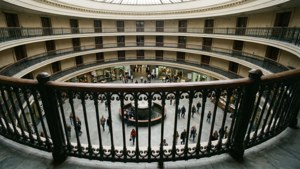 宏偉的圓形中庭，裝飾華麗的鐵欄杆，人們行走。