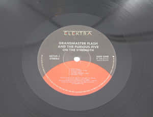 Grandmaster Flash and the Furious Five 專輯《On the Strength》黑膠唱片標籤的特寫。 — 黑色動態圖 壁紙