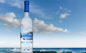 Grey Goose 伏特加酒瓶在海灘上，背景是海洋和天空。