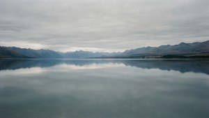 一個平靜的湖泊在陰天下完美倒映周圍的山脈