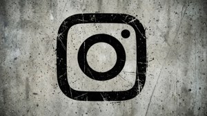 Instagram標誌塗在風化的混凝土牆上，帶有刮痕和斑點。