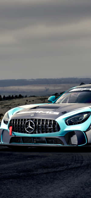 藍綠色平治AMG GT賽車在陰沉天空下的漆黑賽道上。 — Galaxy M06 壁紙