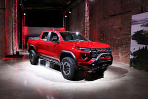 紅色GMC Sierra AT4皮卡車在燈光明亮的磚砌陳列室中展示。 — 3:2 壁紙