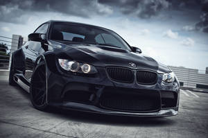 光澤黑色BMW M3跑車配備定制寬體套件停在混凝土屋頂上。