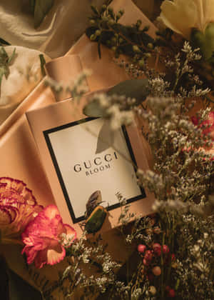 Gucci Bloom 香水瓶被新鮮和乾燥的花朵環繞在緞面表面上。 — Oppo Pad 5 霧面螢幕 壁紙