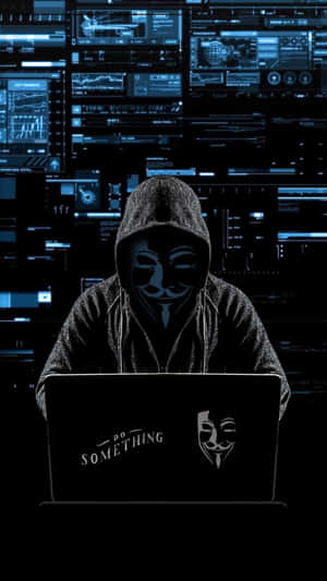 匿名駭客戴面具在筆記型電腦上打字，背後有數位螢幕。