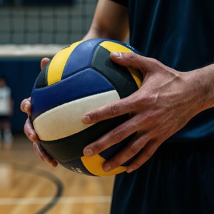運動員在室內球場手持排球，背後可見球網。