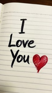 在間線筆記本紙上手寫的訊息「I Love You」和一個紅色心形。