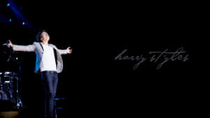 Harry Styles 在舞台上於聚光燈下張開雙臂表演。 — 哈里·斯泰爾斯 壁紙