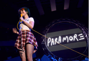 歌手在舞台上表演，身後有Paramore標誌。
