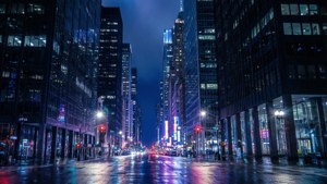 夜間城市街道，濕漉漉的路面反射著霓虹燈和高樓大廈。