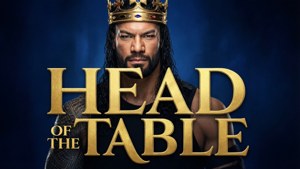 一個摔角手戴著金色皇冠，藍色背景上有金色字母寫著 Head of the Table
