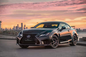 黑色Lexus RC F Track Edition在日落時停泊，背後是城市天際線。 — Surface Laptop 壁紙