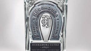 Herradura Ultra Añejo 龍舌蘭酒瓶的特寫，帶有銀色馬蹄鐵標誌。